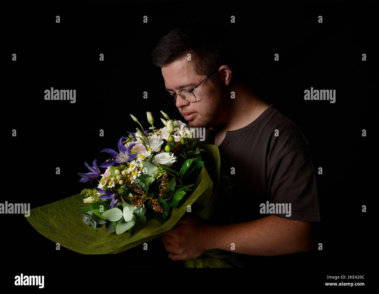 Giovane con sindrome di Down che odora un bouquet di fiori Foto Stock