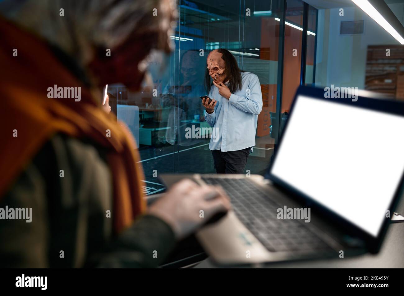 Dipendente zombie che utilizza il telefono cellulare e il computer portatile per il lavoro Foto Stock