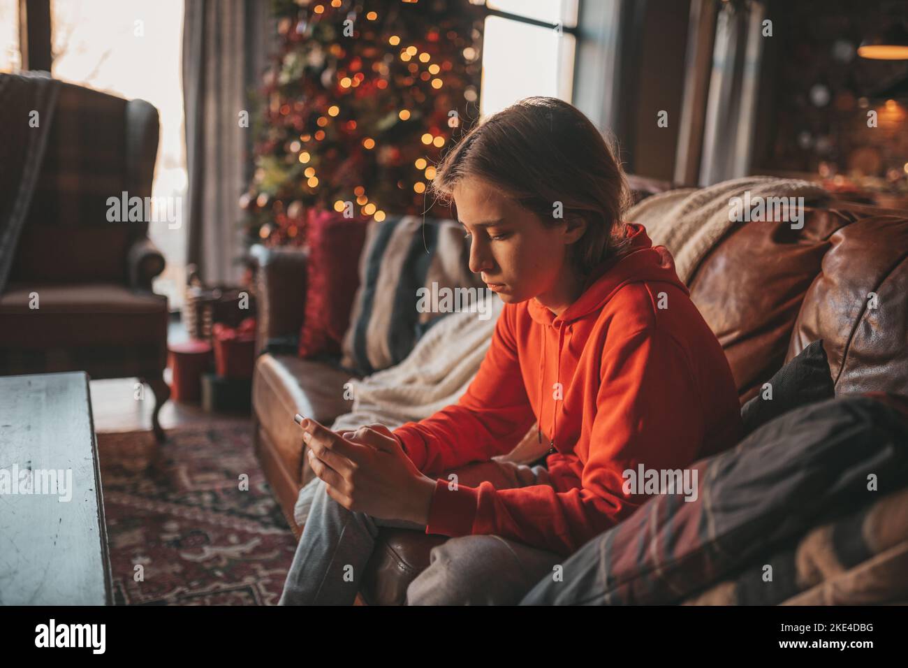 Ragazzo giovane con capelli lunghi sguardo pensieroso occhi tristi umore negativo arrabbiato e piangere a casa. Elegante zoomer gen Z pensive per le vacanze di nuovo anno con Foto Stock