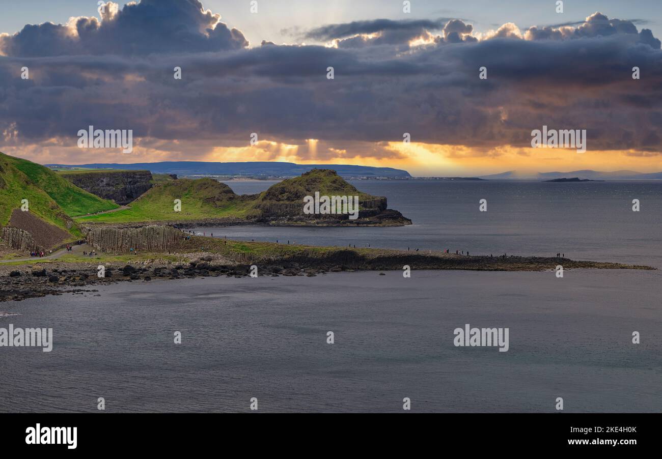 I turisti che si arrampicano sulle antiche colonne basaltiche del Selciato del gigante, patrimonio dell'umanità dell'UNESCO, Causeway Coast, County Antrim, Irlanda del Nord Foto Stock
