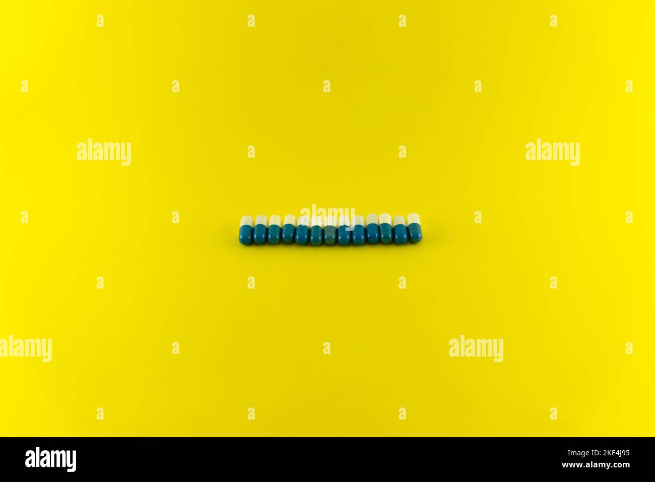 Pillole di colore blu e bianco in fila su una superficie blu. Forniture mediche. Foto Stock
