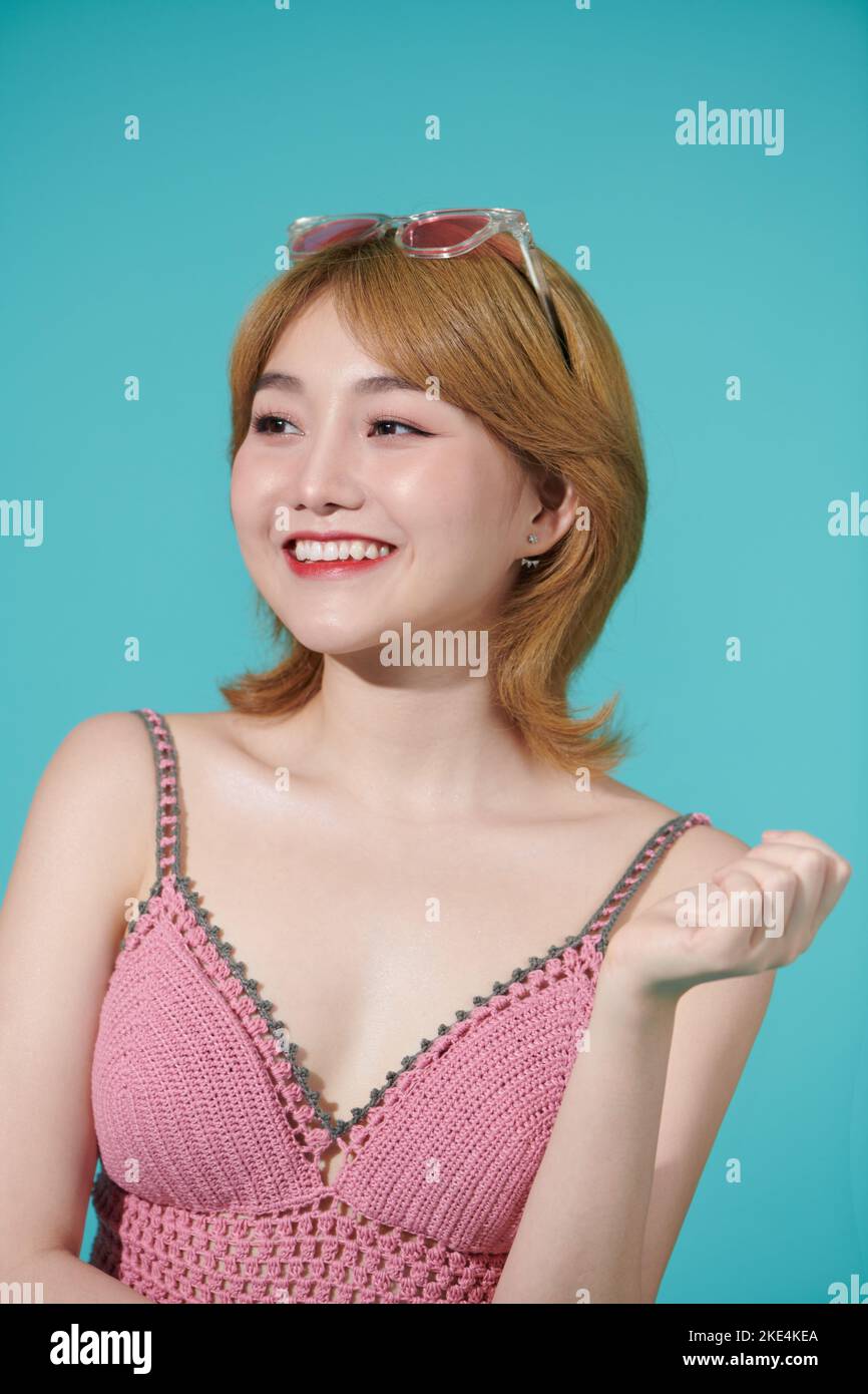 Vita in su ritratto estivo di donna asiatica in studio isolato colore turchese sfondo Foto Stock