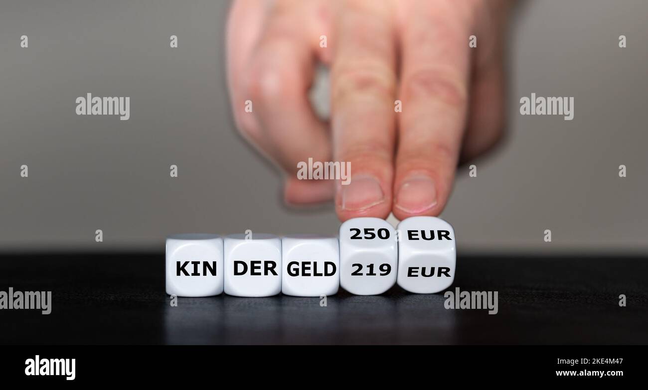 Simbolo per l'aumento dell'assegno per figli in Germania. La mano gira i dadi e cambia l'espressione tedesca 'Kindergeld 219 EUR' in 'Kindergeld 250 E. Foto Stock