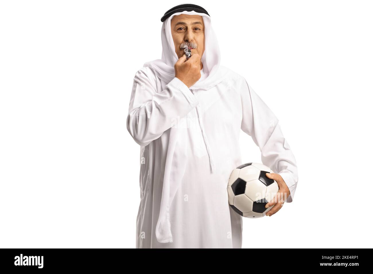Uomo arabo in abiti etnici che tiene un calcio e soffia un fischio isolato su sfondo bianco Foto Stock