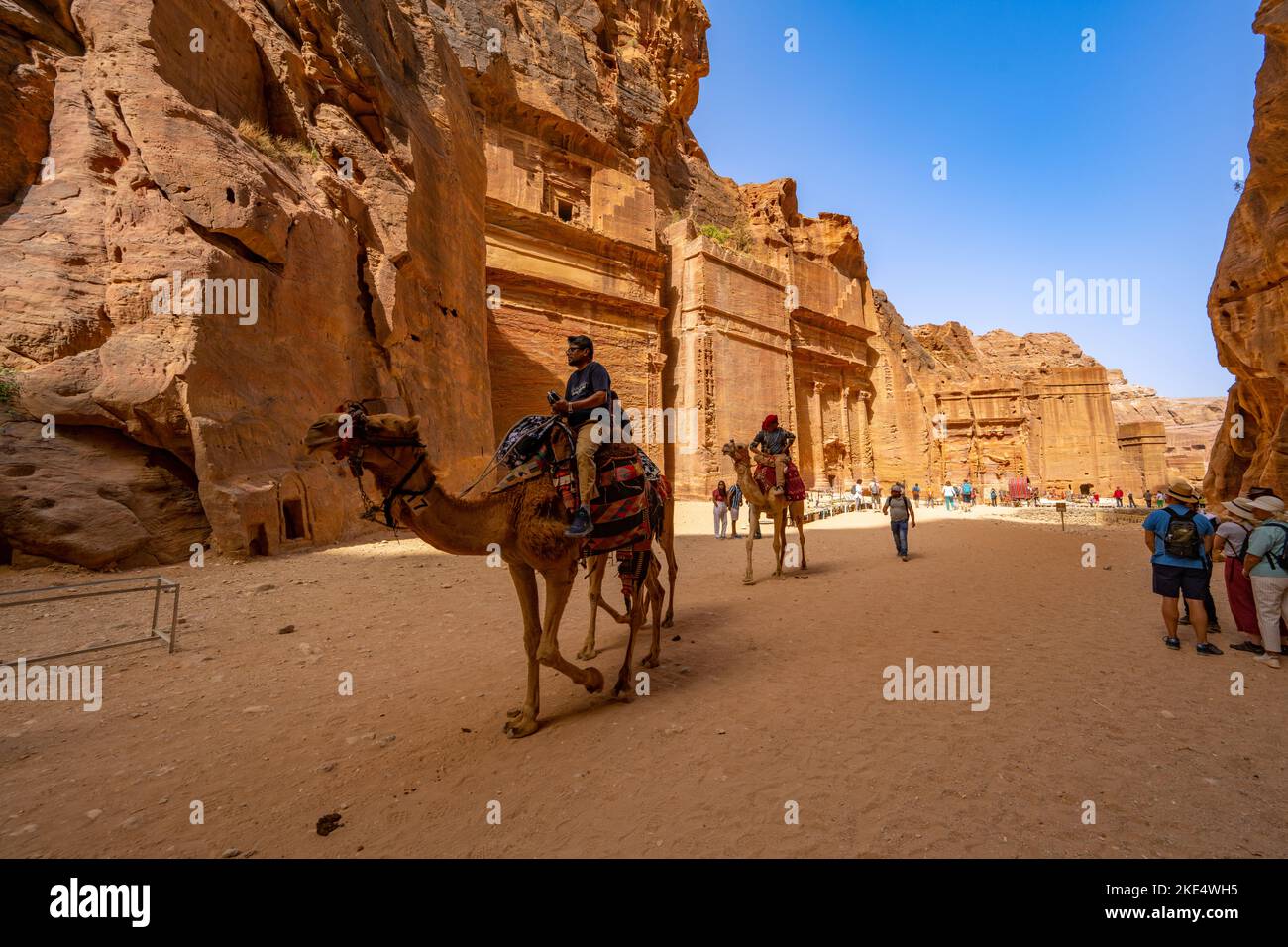 Turisti su cammelli che guardano lungo la strada delle facciate in Petra Giordania Foto Stock