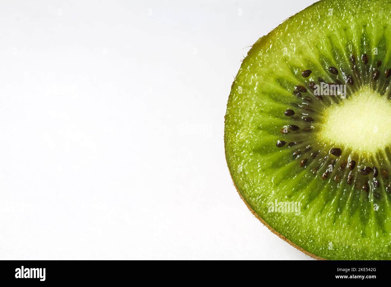 Macro dettaglio primo piano di una mezza fetta isolata fresca matura cruda di kiwi crudo di frutta e nocciolo, sfondo bianco e spazio di copia per il testo Foto Stock