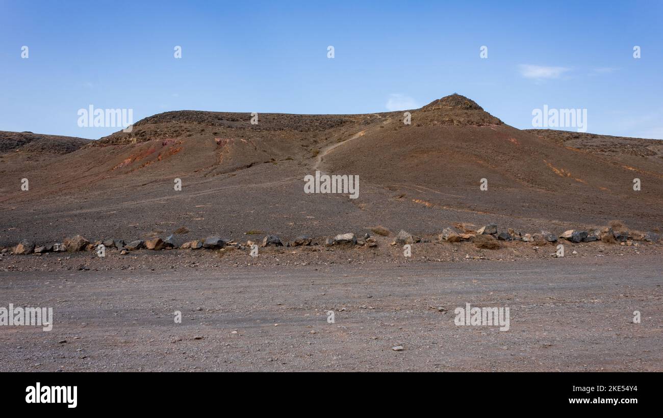 Deserto vuoto in un paesaggio arido verso le montagne vulcaniche vicino Playa Mujeres e la costa Papagayo, Lanzarote, Spagna. Foto Stock