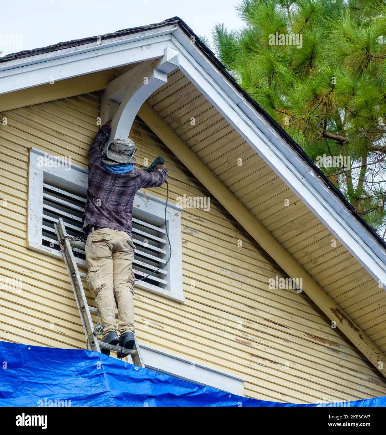 NEW ORLEANS, LA, Stati Uniti d'America - 4 NOVEMBRE 2022: Lavoratore che utilizza la levigatrice elettrica per raschiare la vernice dal legno laterale della casa storica Foto Stock