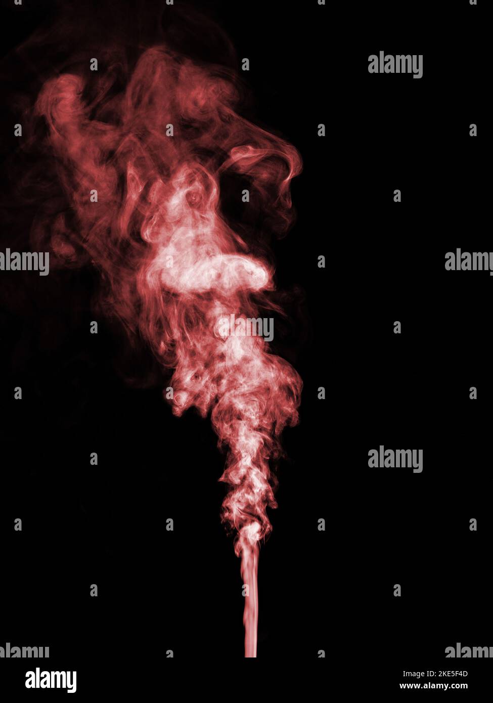 Un getto di fumo rosso si arriccia e rotola e si alza su uno sfondo nero Foto Stock