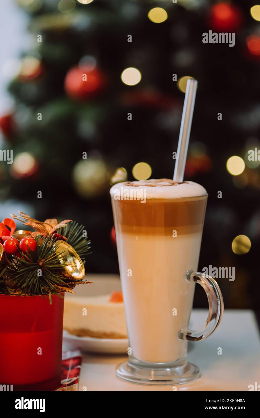 Immagini verticali di tazza di milkshake con paglia su tavola bianca sullo sfondo decorato albero di Natale. Concept drink di festa e felice anno nuovo Foto Stock