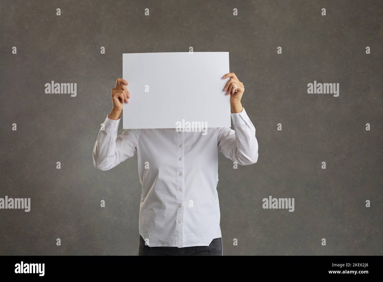 L'uomo tiene un foglio bianco di carta davanti al suo volto, spazio di copia. Foto Stock