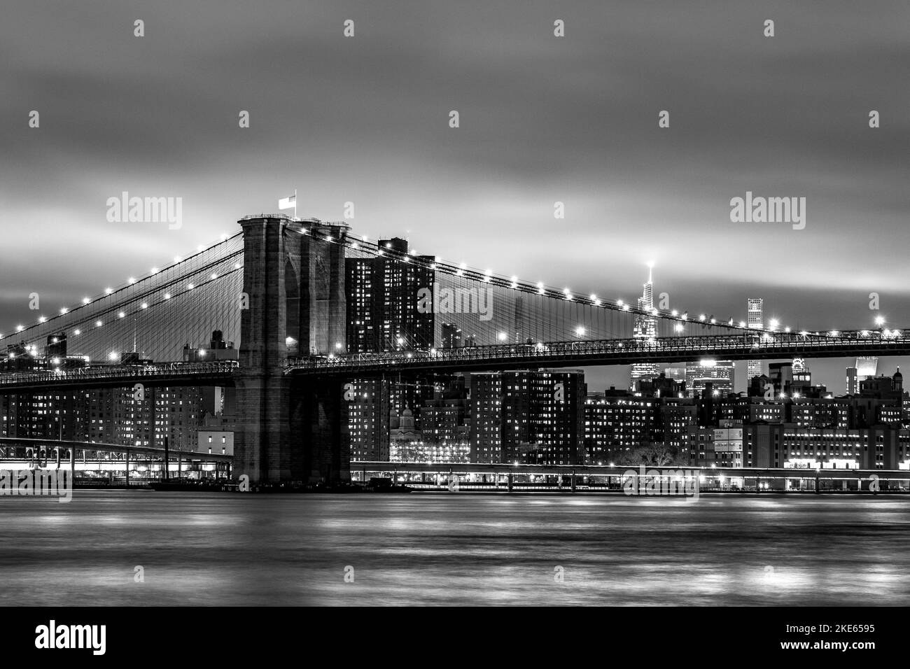 Una vista del Ponte di Brooklyn, sull'East River, in bianco e nero, con uno skyline di Manhattan sullo sfondo Foto Stock