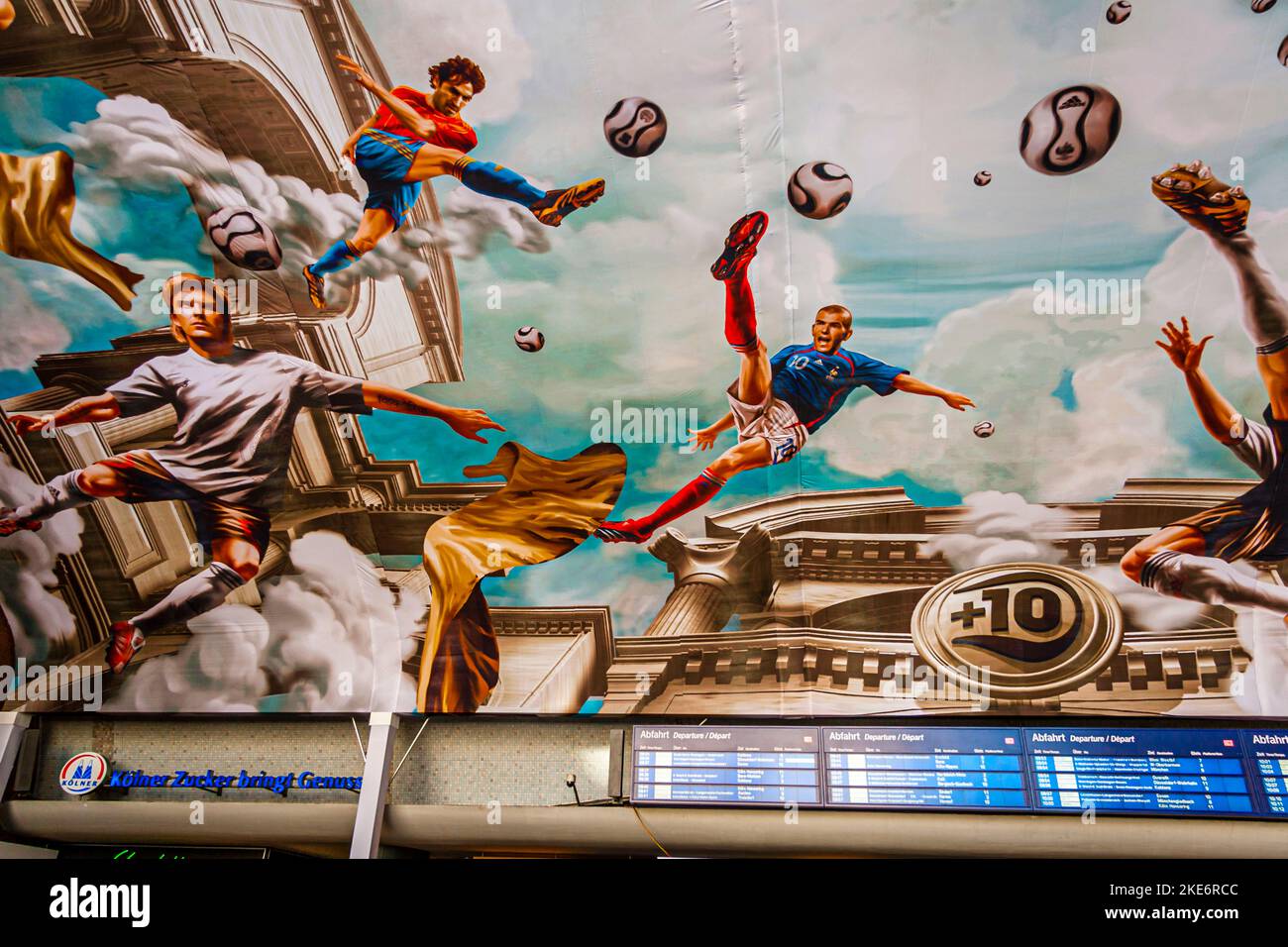 Un murale monumentale sul soffitto della stazione centrale di Colonia raffigura calciatori che saltano tra nuvole e colonne antiche, circondati da palloni fluttuanti. Adidas ha commissionato l'installazione della marouflage, che copre un'area di circa 800 metri quadrati, per celebrare i Mondiali di calcio FIFA del 2006. In un aspetto antico fedele all'originale, giocatori nazionali come Michael Ballack, David Beckham, Zinédine Zidane e Juan Román Riquelme fluttuano ben al di sopra delle teste dei passanti. Colonia, Renania Settentrionale-Vestfalia, Germania Foto Stock