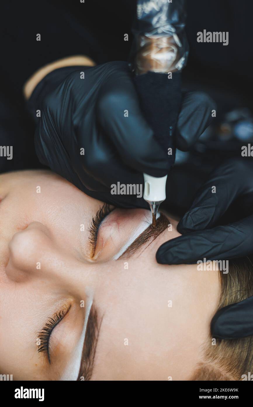 Giovane donna durante la procedura professionale di mappatura delle sopracciglia prima del trucco permanente Foto Stock