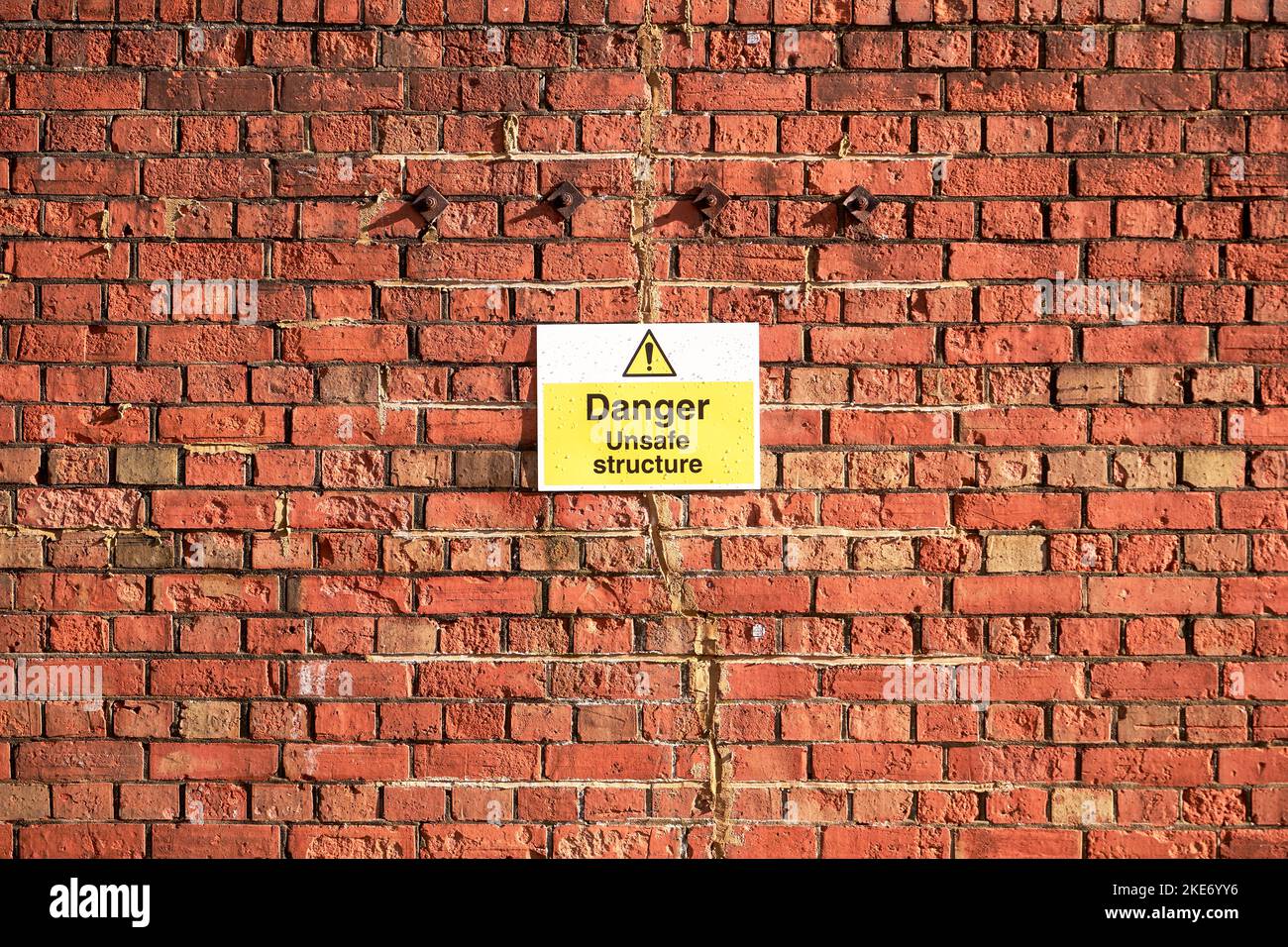Cartello di pericolo struttura non sicura attaccato alla parete di mattoni rossi Foto Stock