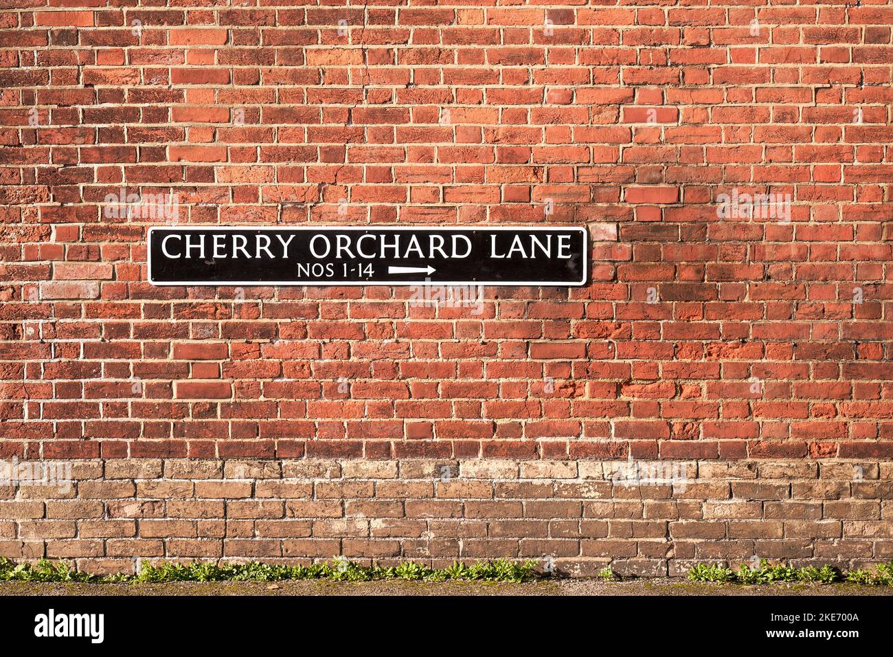 Cartello con il nome della strada Cherry Orchard Lane sul muro di mattoni rossi Foto Stock