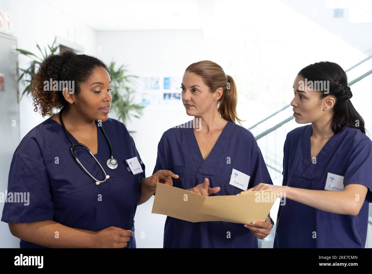 Gruppo eterogeneo di donne che lavorano nel settore sanitario con file che parlano in corridoio ospedaliero Foto Stock