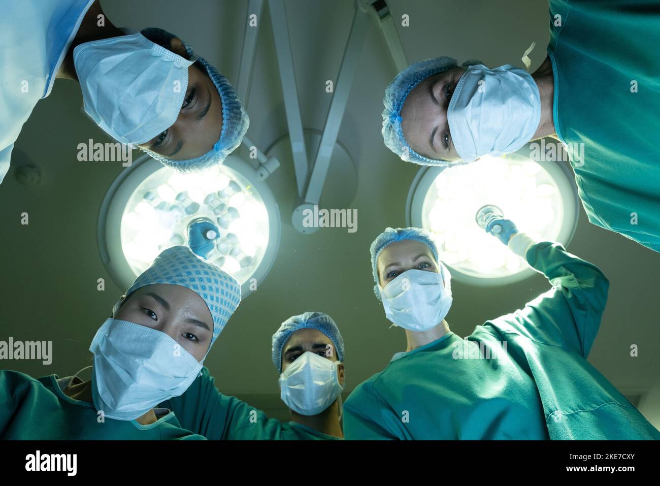 paziente pov di diversi gruppi di chirurghi femminili e maschili in sala operatoria durante l'intervento chirurgico Foto Stock
