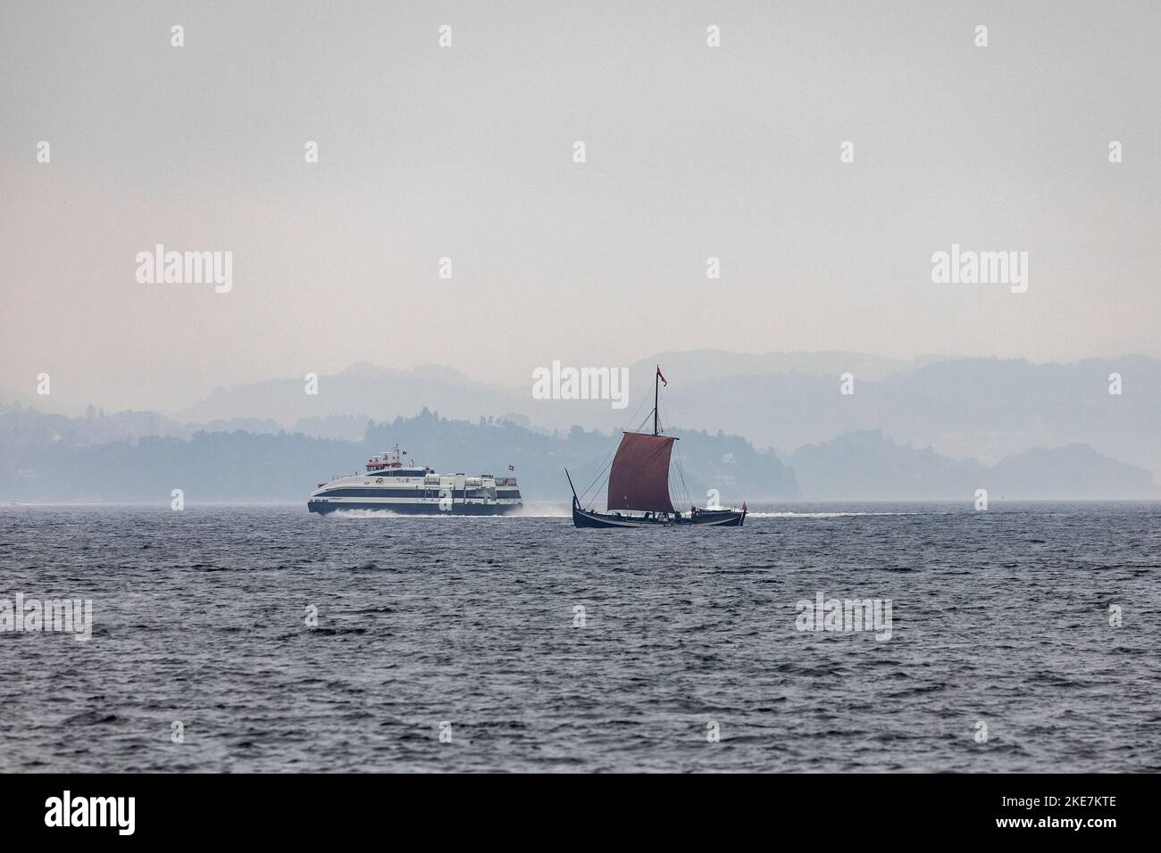 Una copia di una nave a vela vichinga a Byfjorden, che trasporta passeggeri per visite turistiche fuori dal porto di Bergen, Norvegia. Catamarano ad alta velocità F Foto Stock