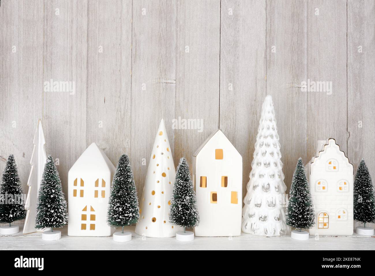 Decorazioni moderne sugli alberi di Natale e case bianche su una mensola su uno sfondo rustico grigio parete Foto Stock
