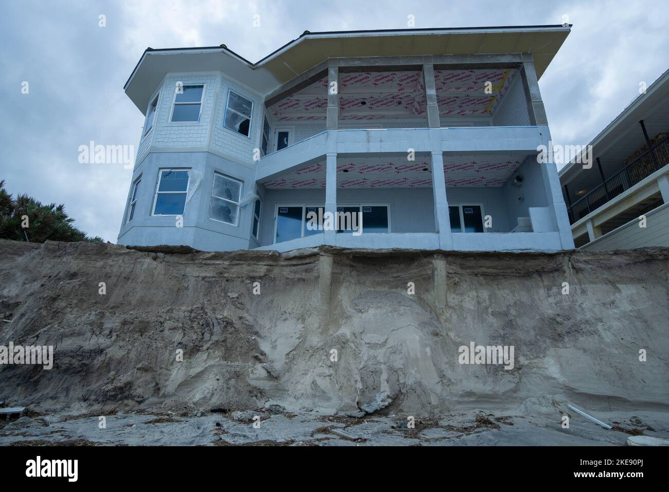Una casa fronte spiaggia in costruzione al 4367 South Atlantic Avenue si trova sul bordo di una scogliera dopo l'uragano Nicole. Foto Stock