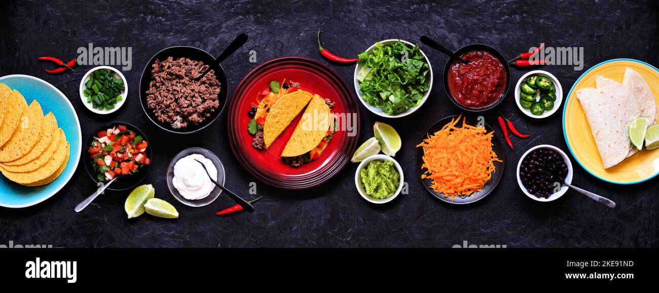 Tavolo da bar Taco con una selezione di ingredienti. Vista dall'alto su uno sfondo scuro per striscioni in ardesia. Buffet di cibo messicano. Foto Stock