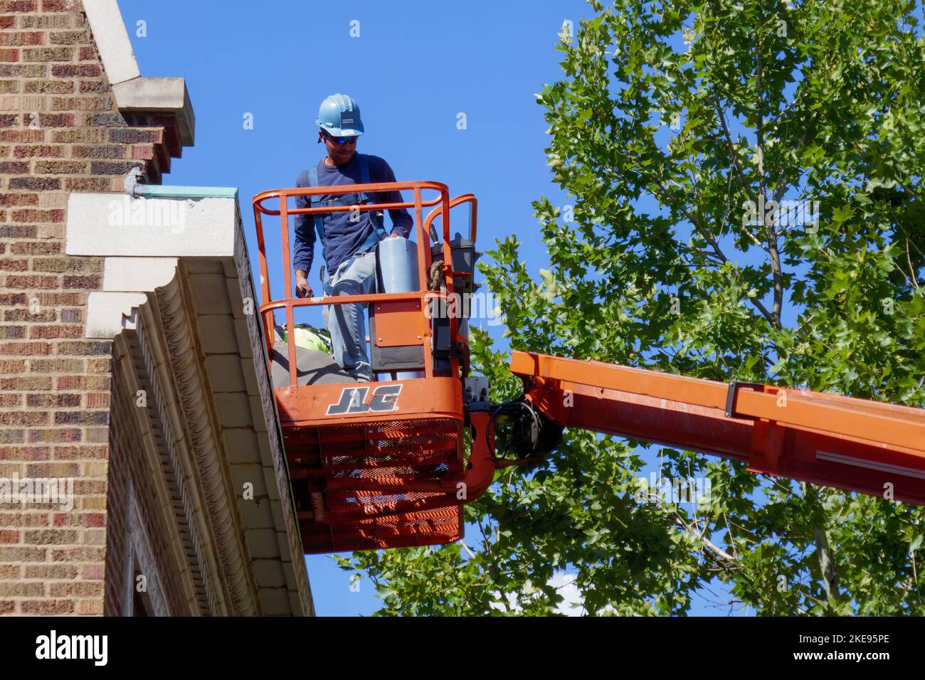 Lavoratore su raccoglitrice ciliegio che fa manutenzione sul tetto. Foto Stock