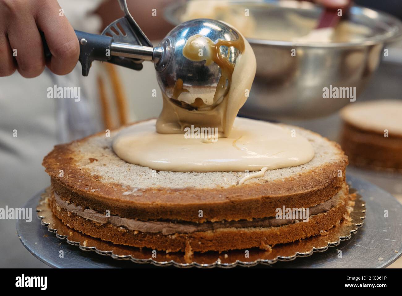 Un panettiere artigianale inserisce un ripieno in una torta a strati Foto Stock