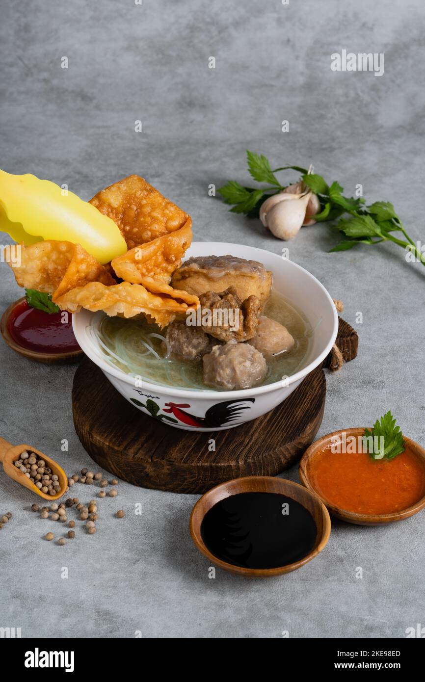 Bakso o polpetta indonesiana servita con zuppa di brodo, tofu, noodle e wonton fritto o gnocchi su un recipiente bianco Foto Stock