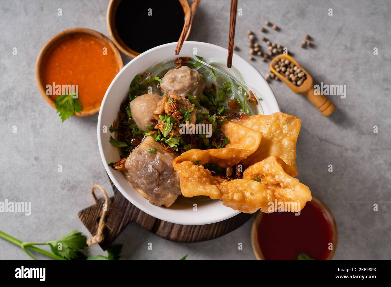 Bakso o polpetta indonesiana servita con zuppa di brodo, tofu, noodle e wonton fritto o gnocchi su un recipiente bianco Foto Stock