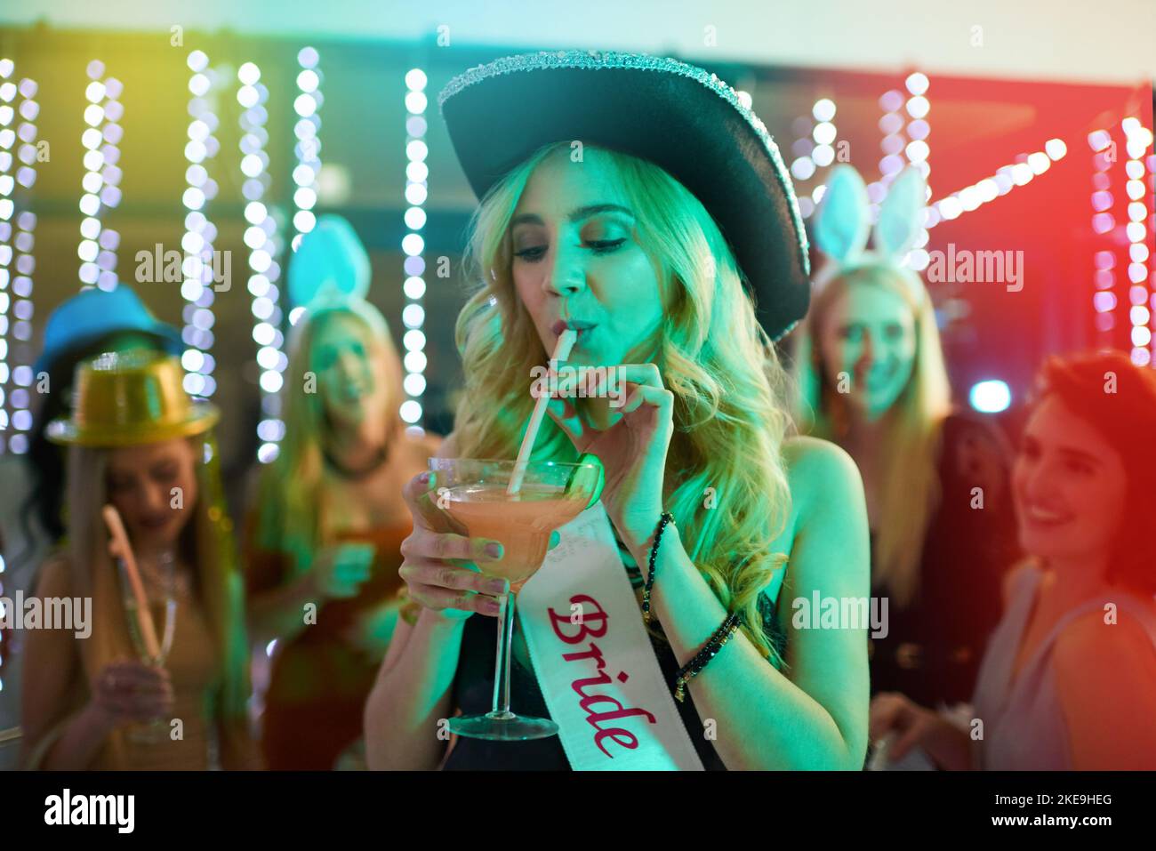 Un ultimo sorso della vita singola: Una giovane donna che beve un cocktail alla sua festa di bachelorette. Foto Stock
