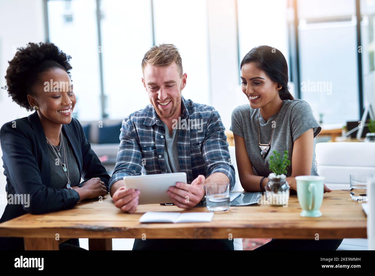 Un team di giovani colleghi che utilizzano un tablet digitale insieme al lavoro. Foto Stock