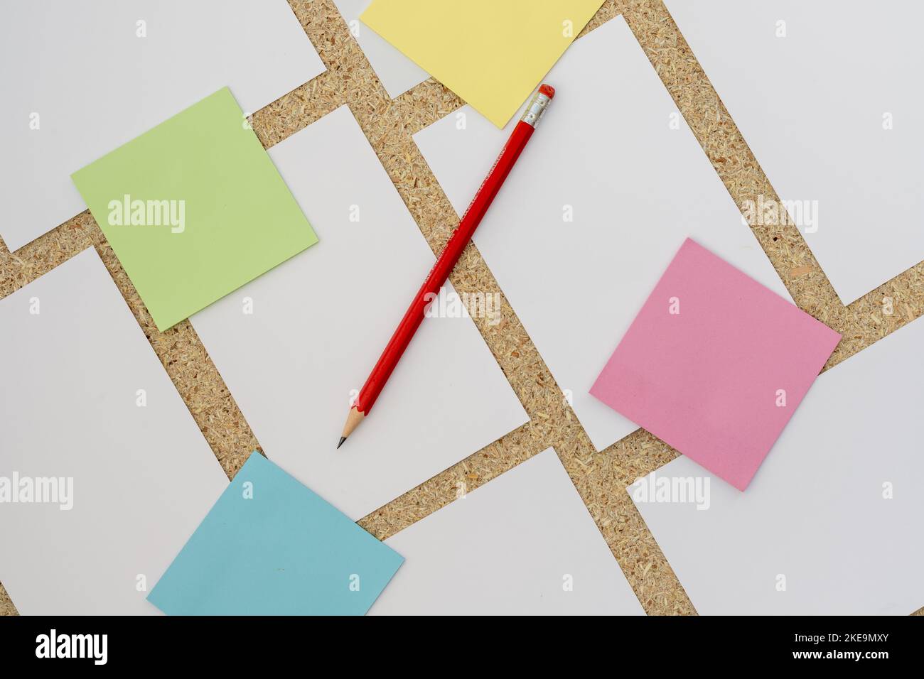 Note adesive colorate su un pannello di sughero con cartolina bianca vuota con matita Foto Stock