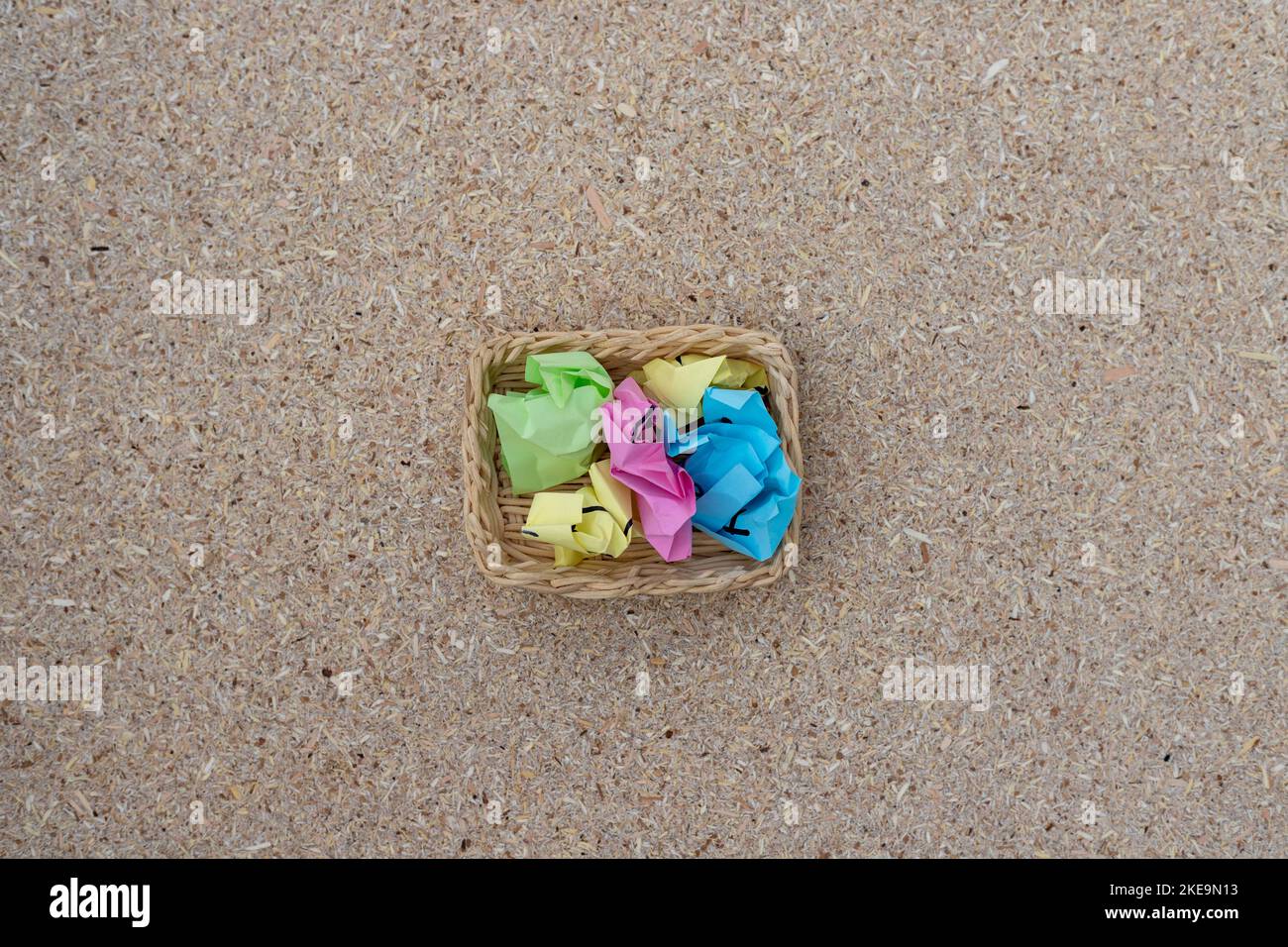 Palline colorate e stropicciate in un piccolo cestino. Concetto di brainstorming. Foto Stock