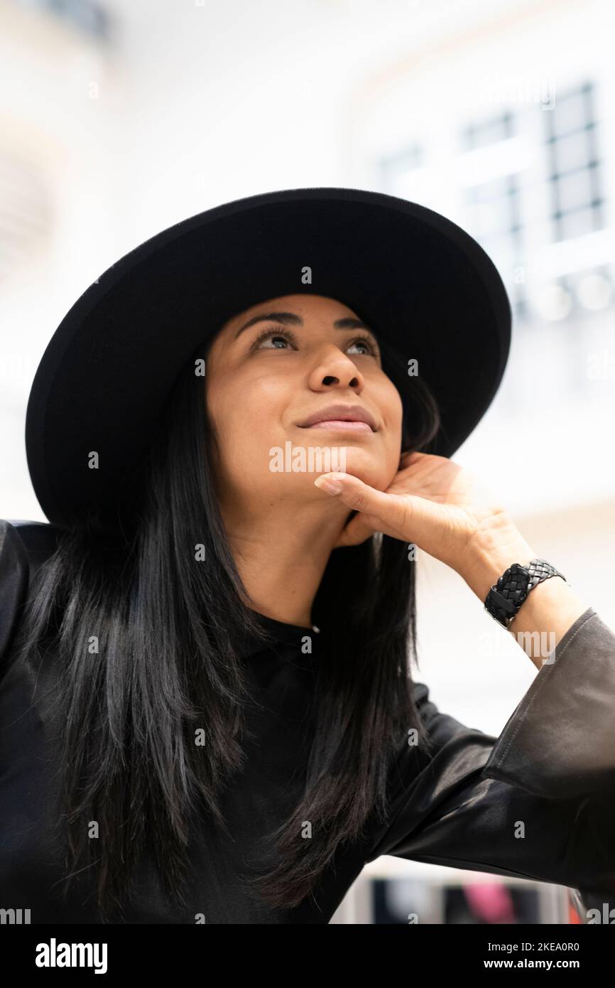 Giovane donna in cappello nero che guarda in alto Foto Stock