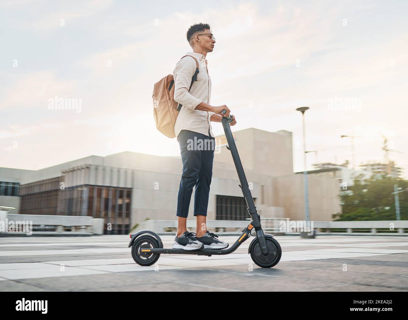 Giovane uomo, scooter ed eco-friendly per un futuro senza emissioni, sostenibile e all'aperto. Viaggi, uomo d'affari informale e guida elettrica Foto Stock