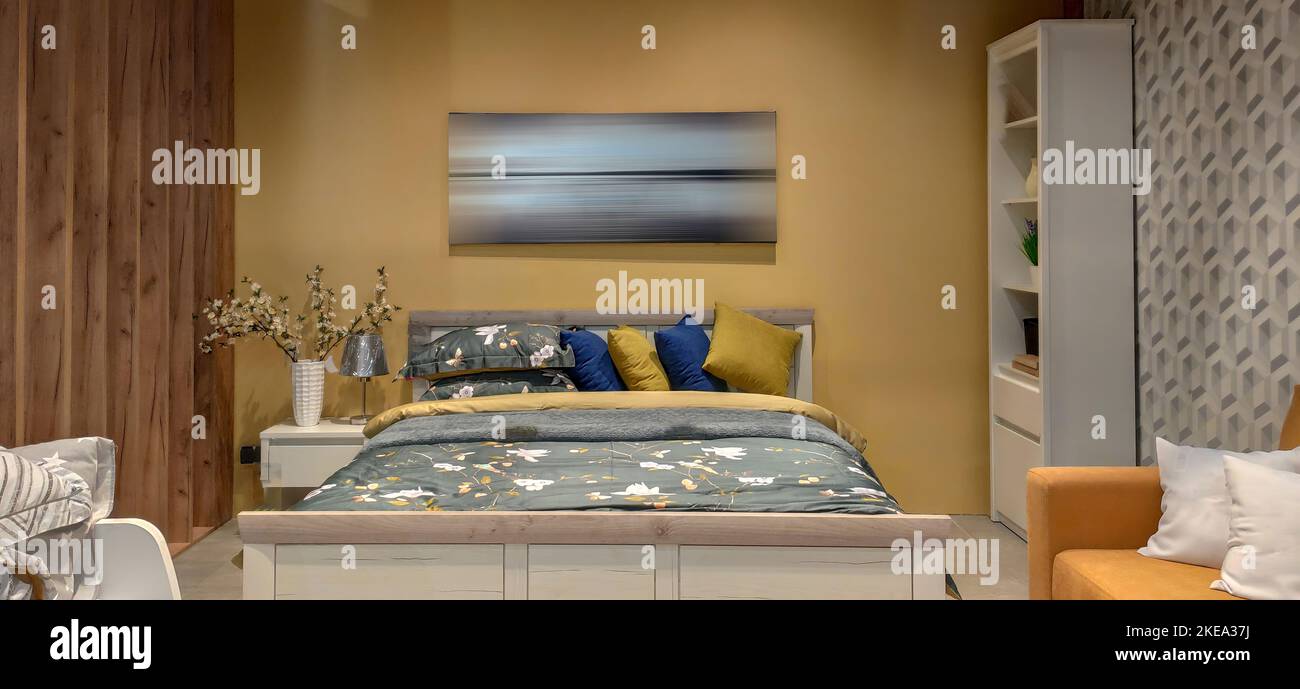 Fotografia interna, ampia camera da letto con letto grande. interno della camera da letto con lenzuola di colore giallo e immagine sulla parete dolce stile casa, legno Foto Stock