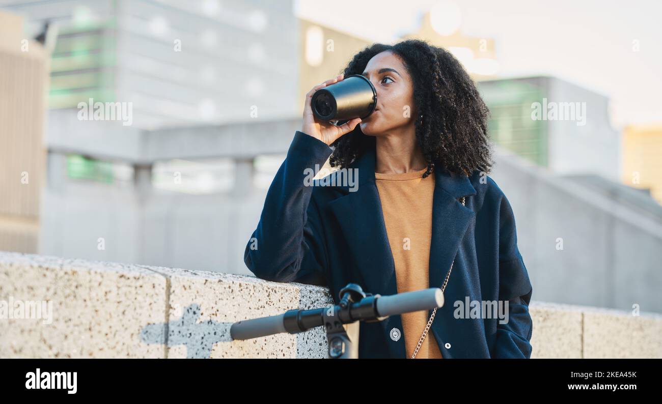 Bere un caffè, uno scooter elettrico e una città con una donna nera in viaggio di lavoro al mattino. Tè, trasporto e impronta di carbonio con un Foto Stock