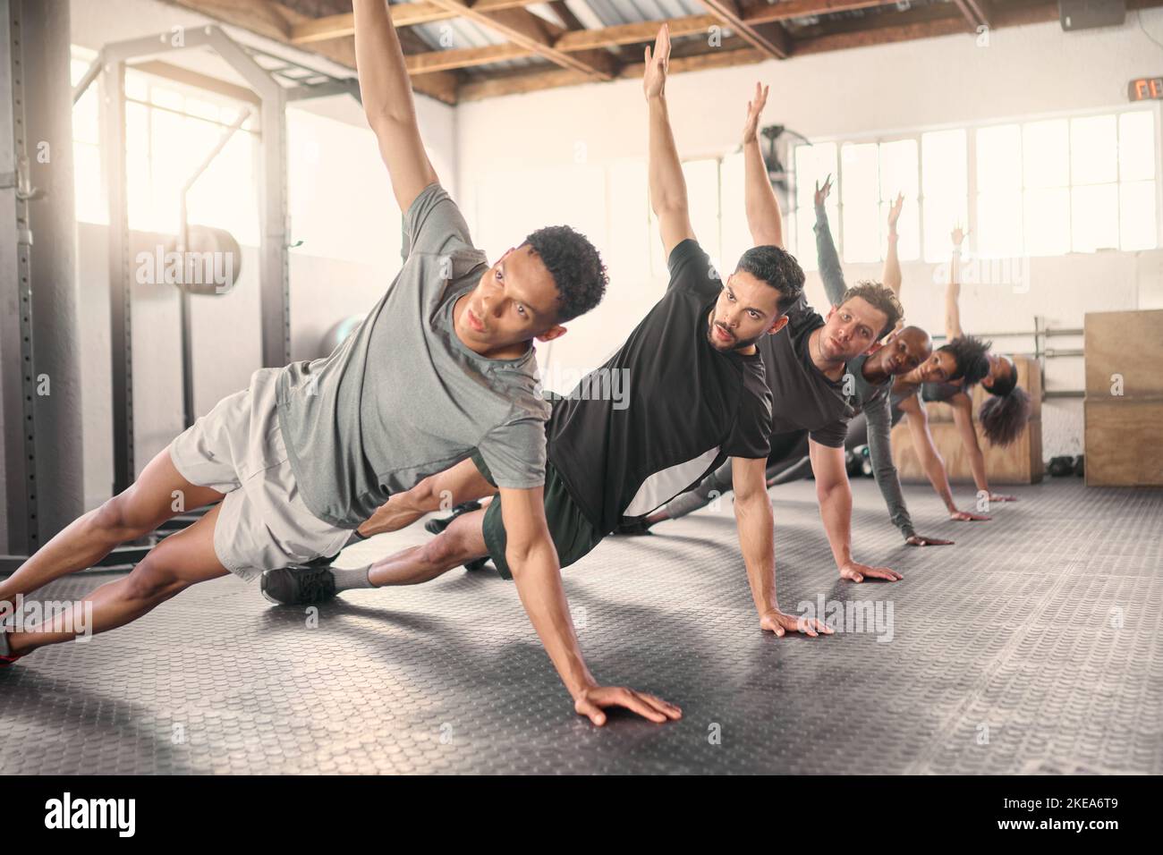 Fitness, esercizio fisico e allenamento con un gruppo sportivo che si allunga insieme in palestra per la salute o il benessere. Allenamento, diversità e coach con un team Foto Stock