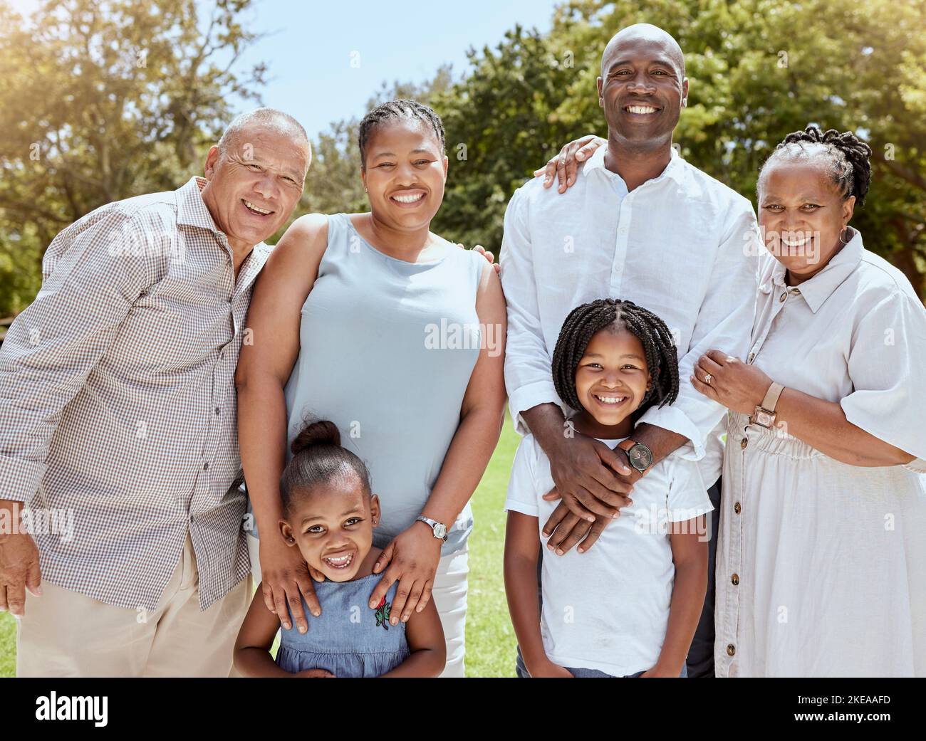 Ritratto di felice famiglia nera con sorriso nel parco, giardino o luogo picnic all'aperto. Uomini, donne e bambini insieme sull'erba in occasione di un evento di famiglia e fare Foto Stock