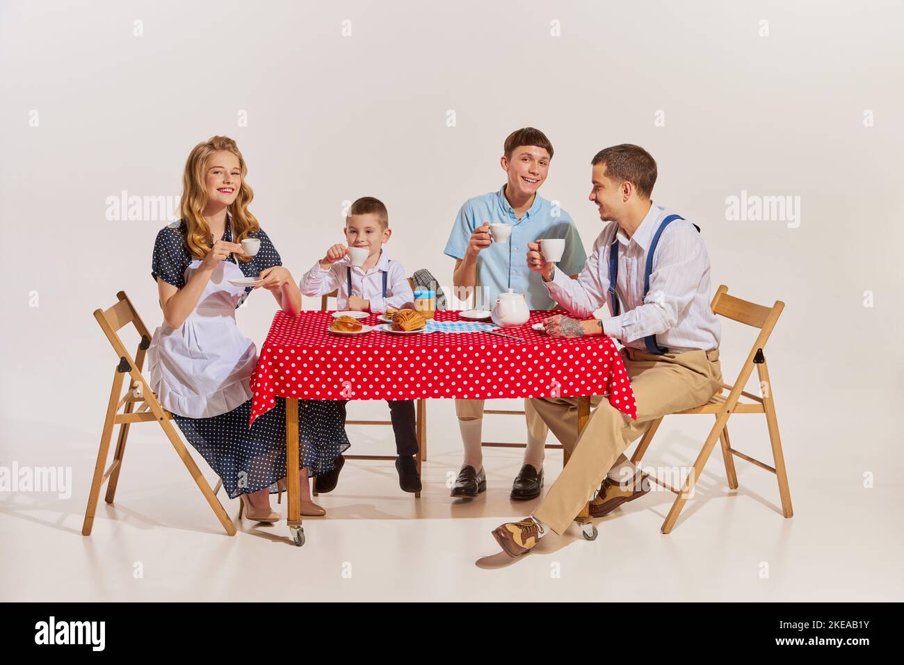 Famiglia allegra, moglie bellissima, due figli e marito seduti al tavolo e a colazione Foto Stock