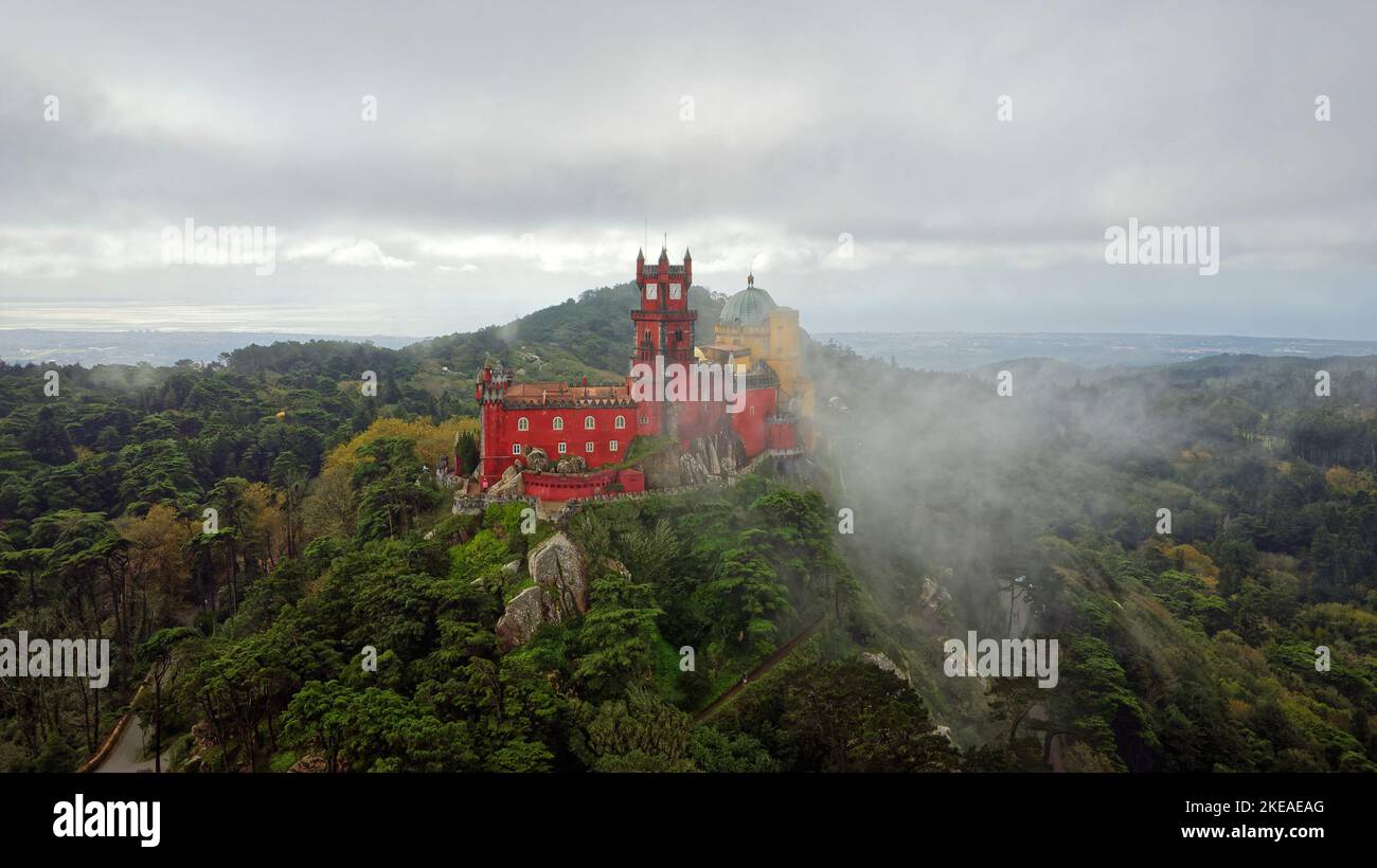 Vista aerea del parco e del Palazzo Nazionale di pena a Sintra, Portogallo durante una giornata di nebbia. UNESCO. Visite storiche. Visite turistiche. Fiaba. Foto Stock