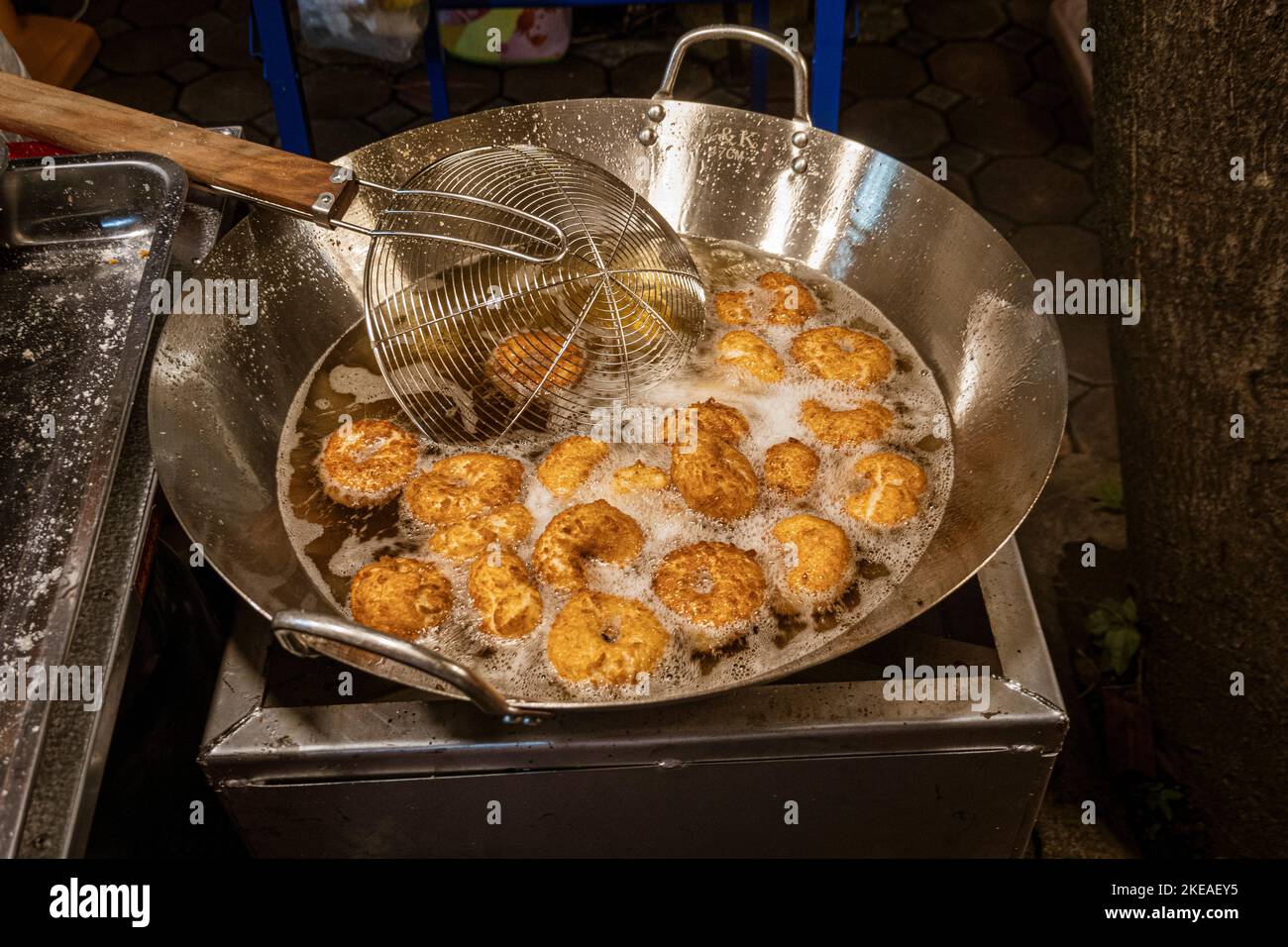 Piccole ciambelle che vengono cucinate al mercato notturno di strada all'aperto. Foto Stock