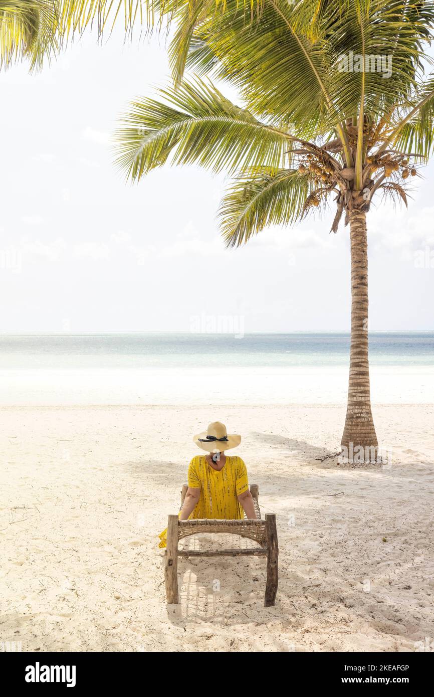 Un turista ammira il mare vicino ad una palma di cocco, durante una giornata di sole, Zanzibar, Tanzania, Africa Foto Stock