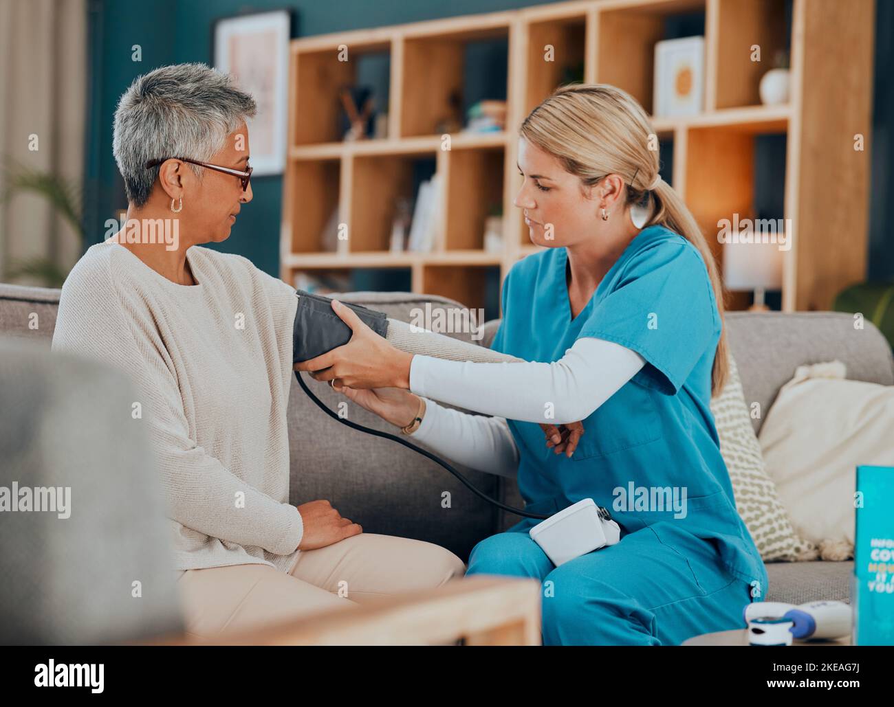 Assistenza sanitaria, pressione sanguigna e donna con medico, home test sul divano o visita medici in appartamento soggiorno. Assistenza senior, infermiere o operatore sanitario con Foto Stock