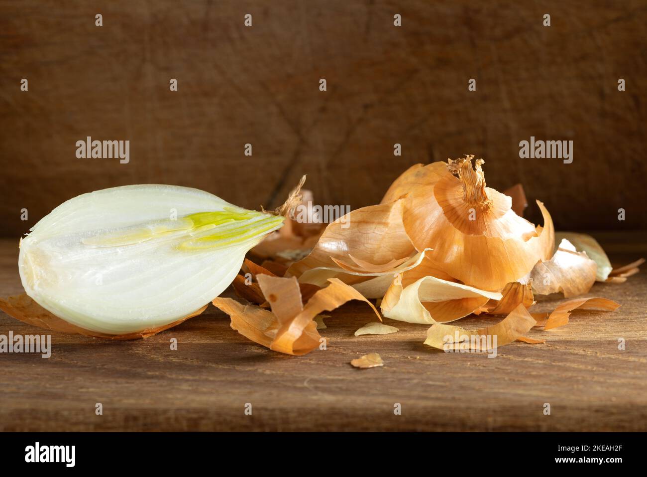 Una mezza cipolla e un sacco di buccia o buccia su sfondo di legno Foto Stock
