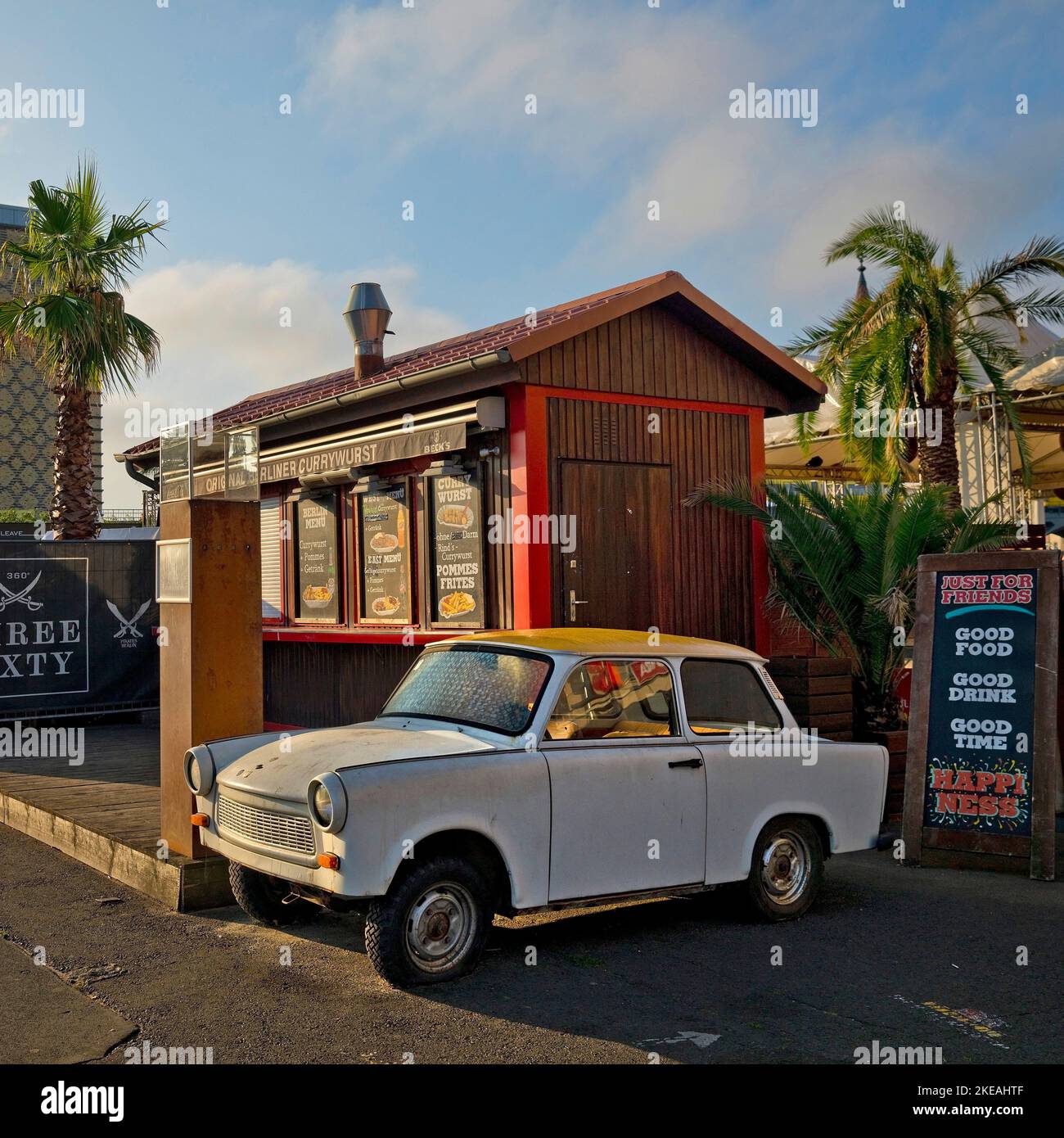 Trabi in uno snack bar con palme a Eierkuehlhaus, East Side Gallery, Germania, Berlino Foto Stock