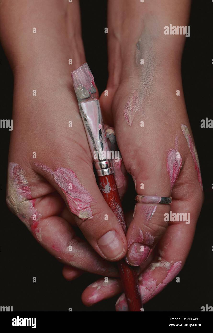 primo piano delle mani di un artista con un pennello a colori Foto Stock