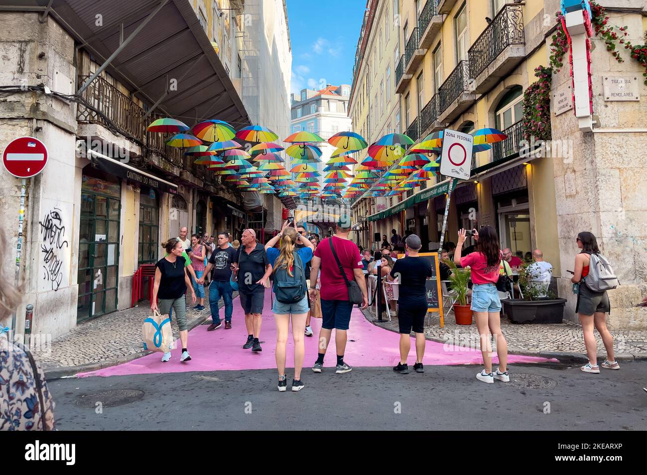 Turisti che pendono fuori sulla strada rosa con ombrelloni colorati Foto Stock