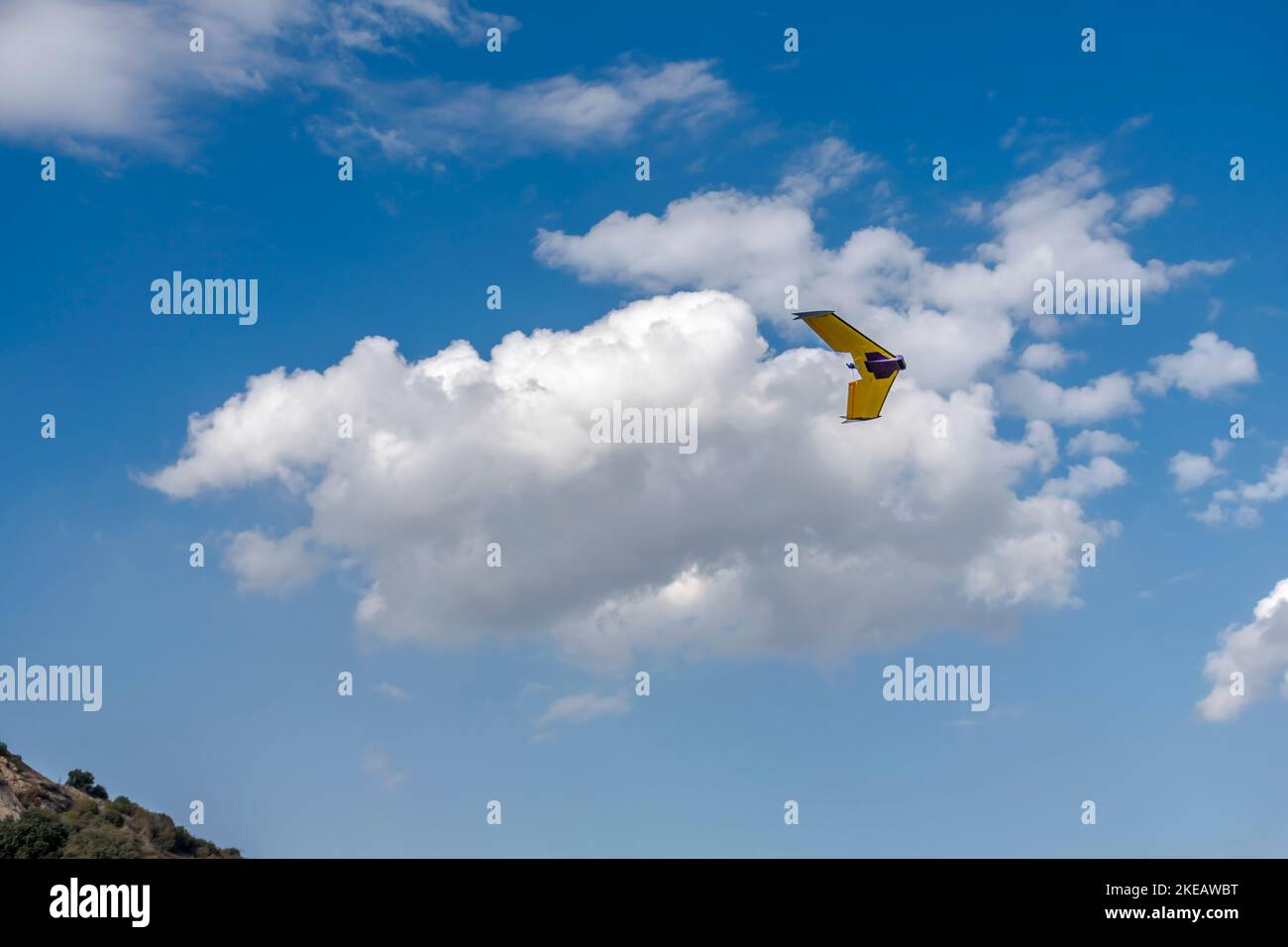 Il drone UAV dell'aeromobile controllato a distanza vola con un'elica, un aereo di colore giallo e viola. Vista ad angolo basso con cielo nuvoloso blu sullo sfondo Foto Stock